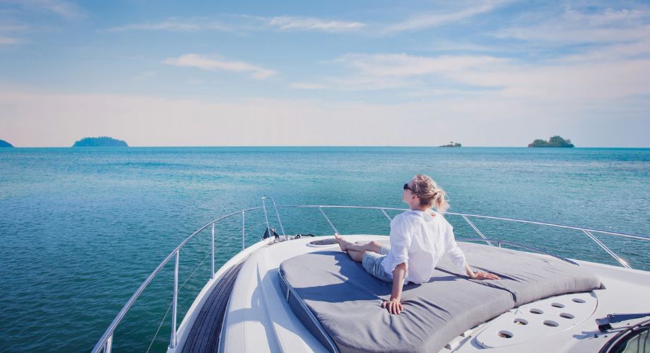 Yacht Sizes | YATCO A woman sitting on a sailing luxury vessel outdoor deck.